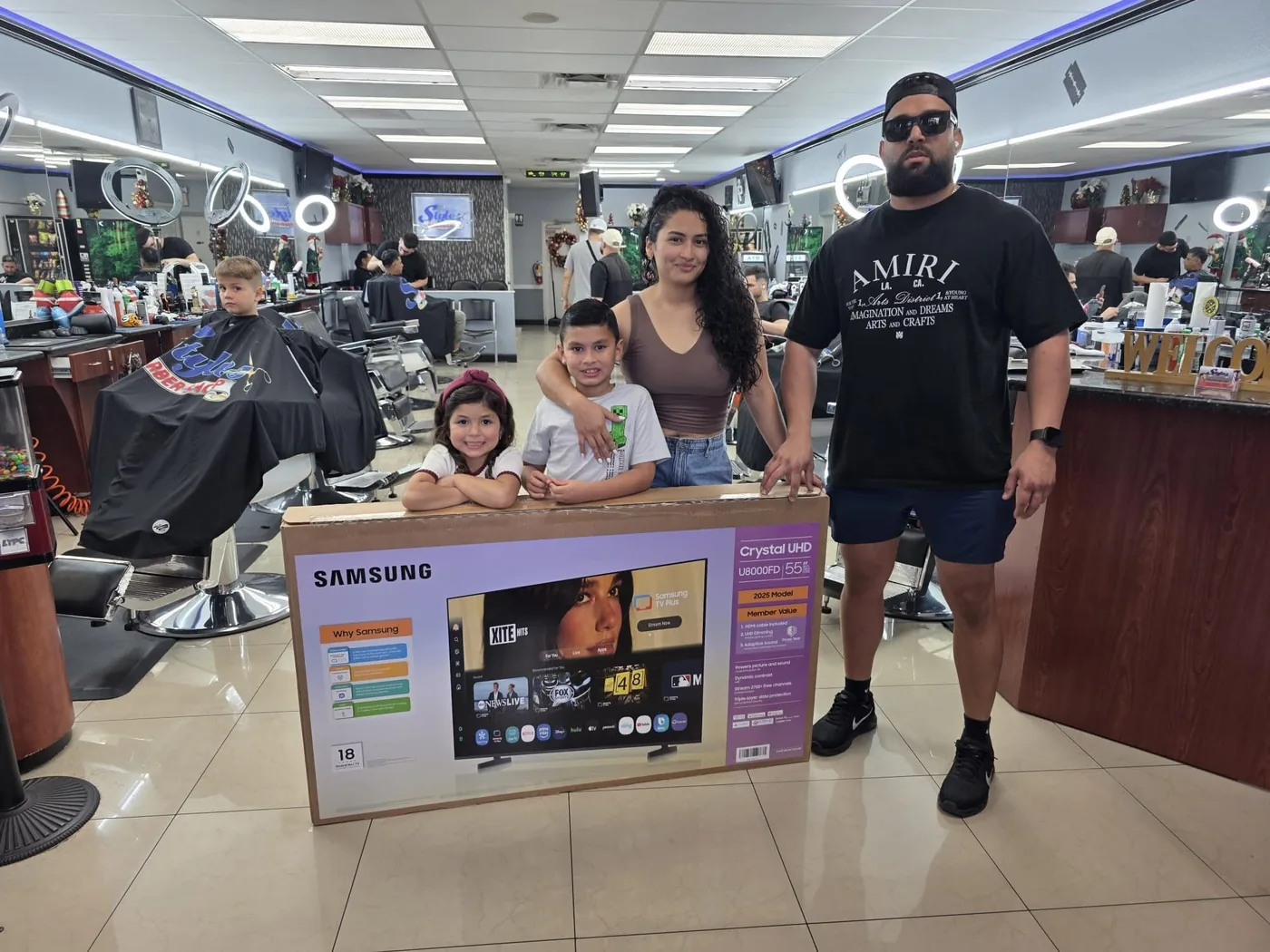 The winning family holding their Samsung 55-inch TV at Styles Barber Shop in Cape Coral